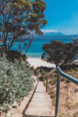 Güneşli bir yaz gününde Opossum Körfezi Plajı 'ndaki manzara. Koyu mavi suları ve açık gökyüzü olan sahilde güzel kıyı şeridini ve kıyılarını yükselten hiç kimse yok.