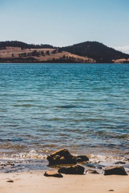 Vahşi Tazmanya manzarası ve Derwent Nehri 'nin el değmemiş turkuaz suyu Hobart' ın güneyindeki Coningham sahilinin yakınlarındaki Legacy Sahili 'nden görüldüğü gibi.