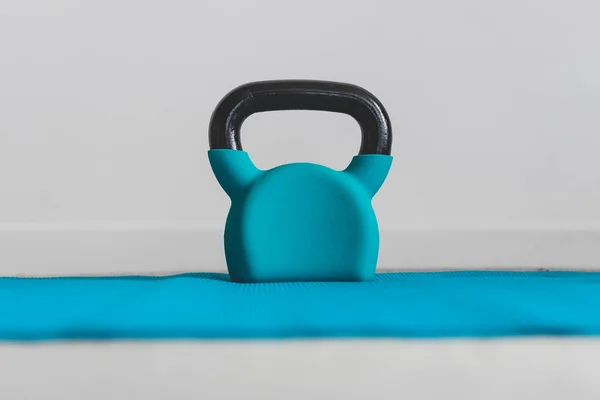 home gym and fitness routines concept, blue yoga mat with kettlebell on top of it shot at shallow depth of field from low perspective