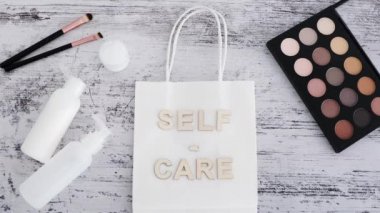 Makyaj malzemeleri ve cilt ürünleri ile çevrili alışveriş poşetindeki kişisel bakım mesajı ve Self, güzellik endüstrisi ve kaplıca treyleri kavramına yakınlaşan kamera