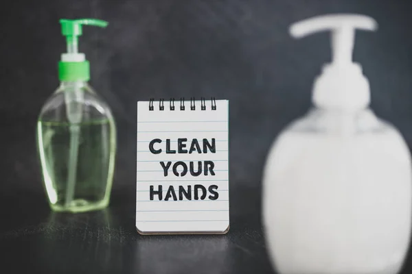 keep your hands clean to fight bacteria and viruses conceptual still-life, hand sanitizer and liquid soap next to memo with Clean your Hands text