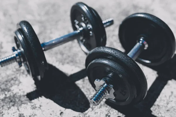 keeping fit and exercising outdoor or at home, set of heavy dumbbells on concrete path in a backyard