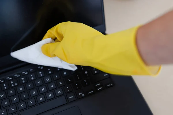 practice good hygiene against viruses and bacteria, hand with cleaning gloves disinfecting laptop keyboard with wipe
