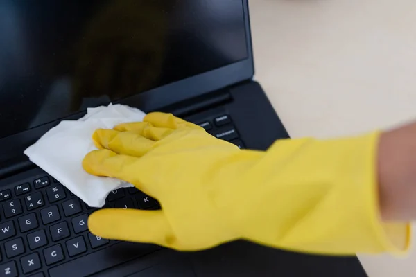 practice good hygiene against viruses and bacteria, hand with cleaning gloves disinfecting laptop keyboard with wipe