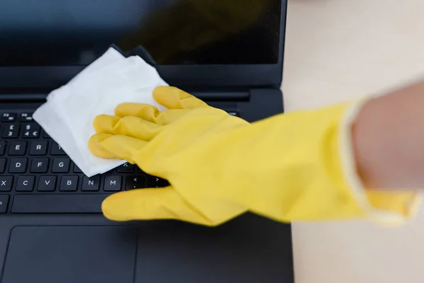 practice good hygiene against viruses and bacteria, hand with cleaning gloves disinfecting laptop keyboard with wipe