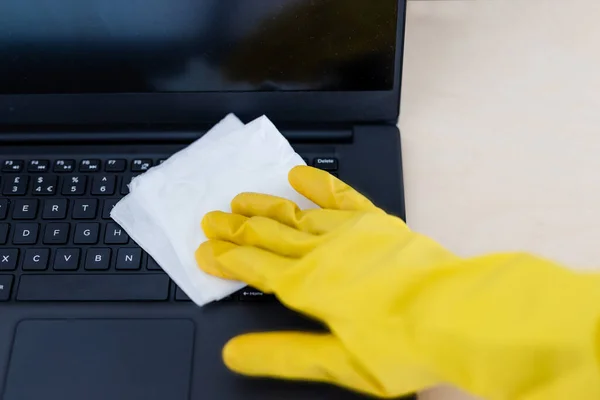 practice good hygiene against viruses and bacteria, hand with cleaning gloves disinfecting laptop keyboard with wipe