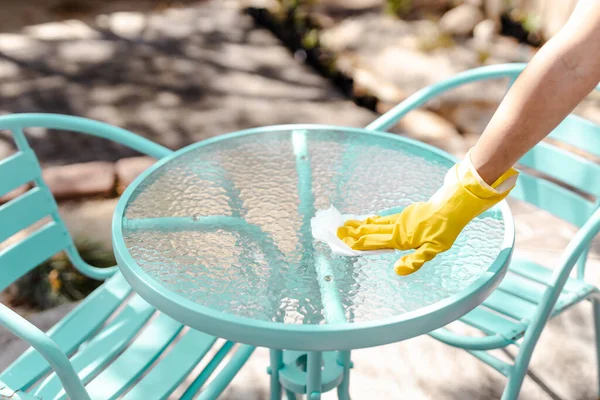 practice good hygiene against viruses and bacteria, hand with cleaning glove disinfecting outdoor cafe table