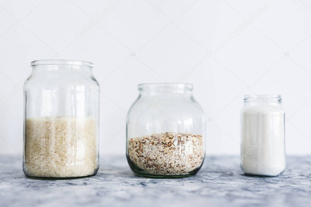 healthy non-perishable food ingredients for vegan pantry, glass jars with oats flour and rice 
