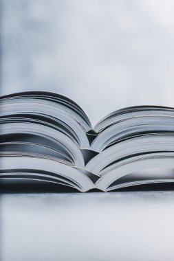 Eğitim ve kendini geliştirme konsepti, her öğreticinin üzerine yığılmış açık kitap yığını göz hizasından sığ alan derinliği ile çekilen