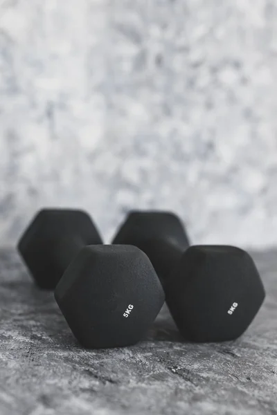 sport and fitness gear, set of black dumbbells on concrete shot at shallow depth of field