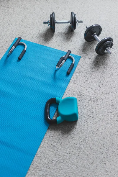 home gym concept, room with dumbbells kettlebell foam roller and push-up handles on yoga mat to workout from home