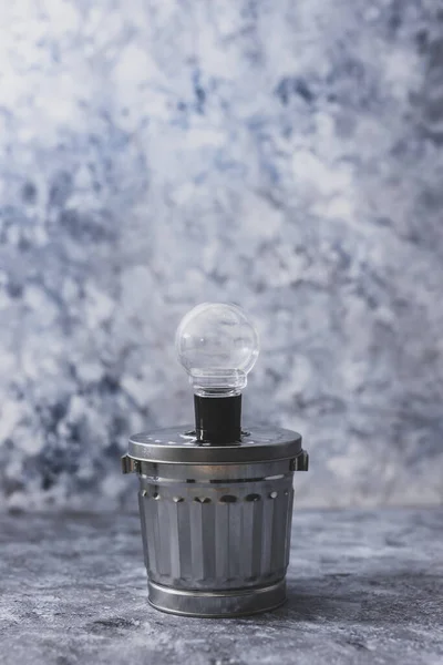 ideas for waste management and recycling concept, light bulb on tp of garbage bin shot at shallow depth of field edited with desaturated tones and minimalist look