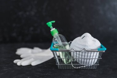 Market alışverişi ve virüs salgınları sırasında markette nasıl güvende kalınacağı, yüz maskesi dezenfektanı ve eldivenli alışveriş sepetinin salgından korunmak için nasıl kullanılacağı.