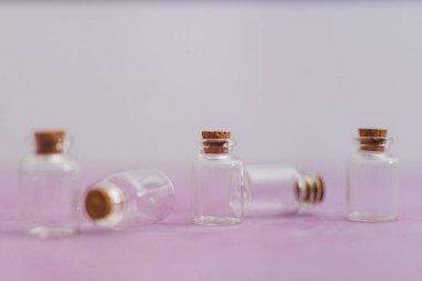 Cilt bakımı ve güzellik ürünleri konsepti, pembe ve beyaz arka planda minimalist kompozisyona sahip bir grup temel yağ şişesi.