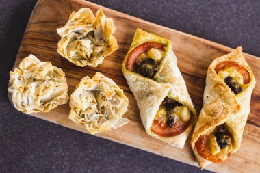 Sağlıklı bitkisel yemek tarifleri konsepti, fileto hamur bardakları ve vegan peynirli pesto ve domates domatesli puf böreği zarfları.