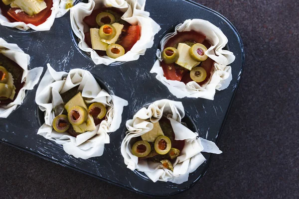 healthy plant-based food recipes concept, filo pastry cups with vegan filling made of tomatoes olives pesto and dairy-free cheese