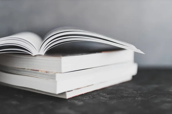 education and self-improvement, stack of books with one open on top of themshot from eye level with shallow depth of field