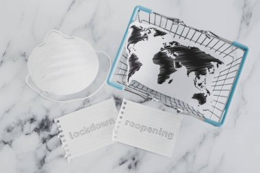 Covid-19 'un küresel salgınından sonra normale dönmek, dünya haritası ve eldivenli maske ile alışveriş arabasının yanındaki kilitlenmeye karşı.