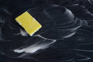 disinfecting and cleaning against bacteria and viruses, yellow sponge with soap marks all around it on top of surface to be sanitized clipart