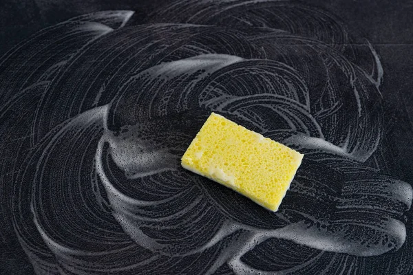 disinfecting and cleaning against bacteria and viruses, yellow sponge with soap marks all around it on top of surface to be sanitized