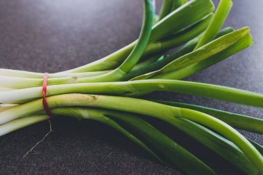 sağlıklı bitkisel malzemeler, mutfak tezgahında bir demet taze soğan.
