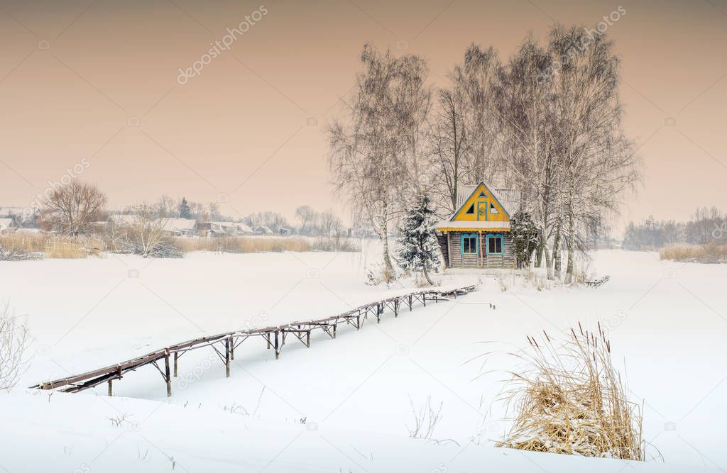 orange sunset above winter landscape with farmhouse