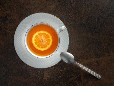 Bir fincan limonlu çay ve çay kaşığı da ark masasında.