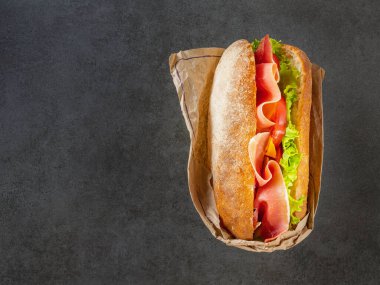 Ciabatta, prosciutto ve sebzelerle kaplanmış koyu arkaplanda fotokopi alanı ile birlikte.