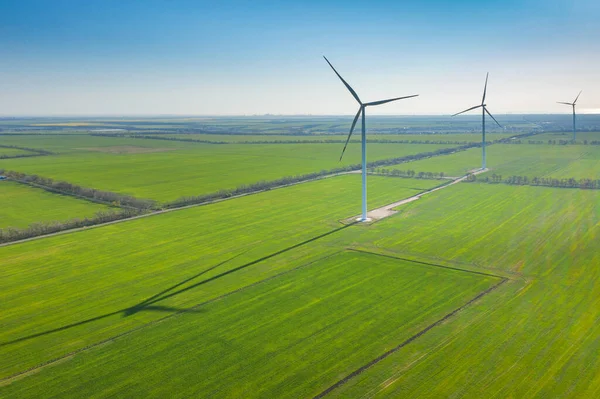 蓝天下有长影的绿麦田风力发电机组航向视图及复制空间 — 图库照片
