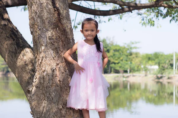 Маленька азіатська дівчинка з деревом біля лагуни — стокове фото