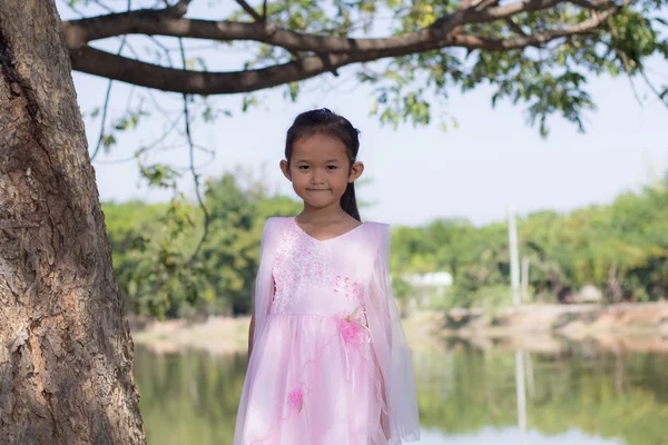 Pouco menina asiática com árvore perto da lagoa — Fotografia de Stock