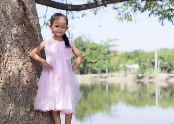 Little asian girl with tree near lagoon — Stock Photo, Image