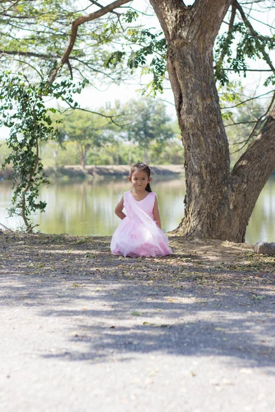 Little asian girl with tree near lagoon — Stock Photo, Image