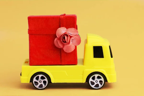 toy car delivering a large present red box. Home delivery of  gifts