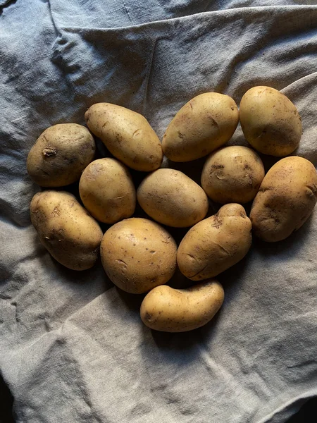 Heart of fresh organic dirty potatoes on linen fabric