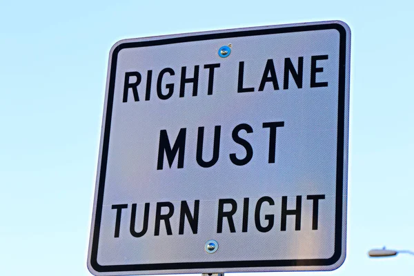 Sign of Right lane must turn right background of white color.Right lane turns rights ahead sign in white color in USA main street.Signs and instructions for drivers, pedestrians and passers-by.Signpost in public street, \