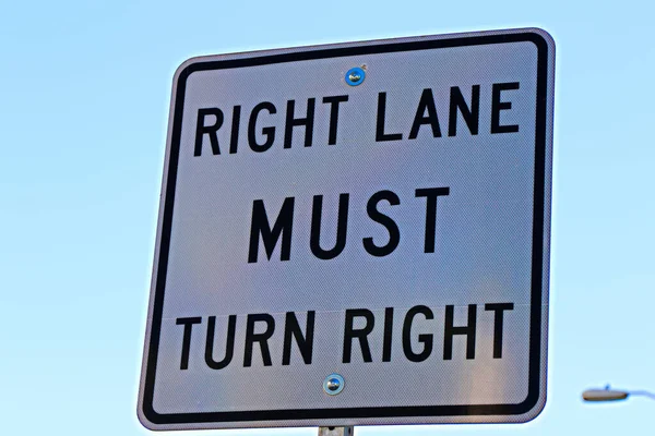 Sign of Right lane must turn right background of white color.Right lane turns rights ahead sign in white color in USA main street.Signs and instructions for drivers, pedestrians and passers-by.Signpost in public street, \