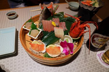 Japonya 'ya özgü otantik saşimi tabağı. Yeşil yapraklı çiğ balıklarla Japon yemek tarzı. Sinema tarzında hafif meşaleli.