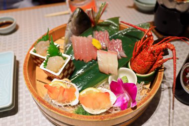 Japonya 'ya özgü otantik saşimi tabağı. Yeşil yapraklı çiğ balıklarla Japon yemek tarzı. Sinema tarzında hafif meşaleli.