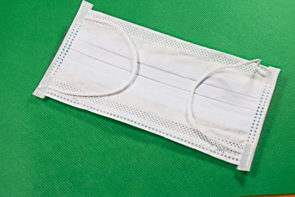 Surgical protective mask. Medical respiratory bandage face Shortage of masks on a green color background. prevention of the spread of virus and pandemic COVID-19.Mask export regulations.