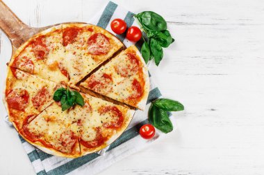 Salam ve peynirli sıcak gerçek Pepperoni İtalyan Pizzası. Süslü ve dilimli beyaz ahşap masada geleneksel pepperonili pizza. Logon için boşluğu kopyala. Reklam için ideal 