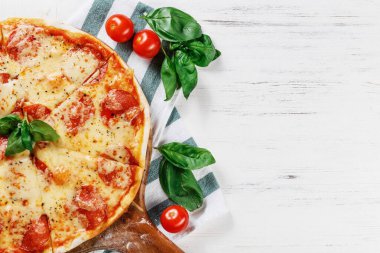 Salam ve peynirli Acılı Gerçek Pepperoni İtalyan Pizzası 'nın yarısı. Beyaz ahşap masanın üzerinde geleneksel pepperonili pizza var. Logon için boşluğu kopyala. Reklam için ideal 