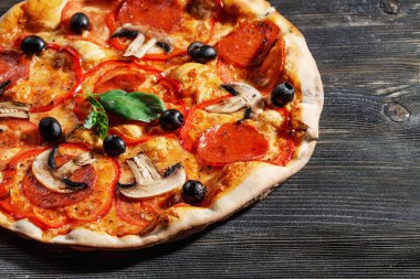 Tahta masadaki İtalyan Pizzası 'nın yakın plan görüntüsü. Salamlı, mantarlı, fesleğenli, zeytinli, biberli ve peynirli gerçek sıcak Pizza. Pizzeria menüsü için güzel. Yüksek kalite  