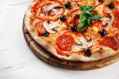 Tahta masadaki İtalyan Pizzası 'nın yakın plan görüntüsü. Salamlı, mantarlı, fesleğenli, zeytinli, biberli ve peynirli gerçek sıcak Pizza. Pizzeria menüsü için güzel. Yüksek kalite  