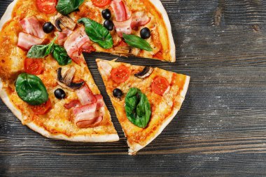 Mantarlı, fesleğenli, domatesli, zeytinli ve peynirli İtalyan Pizzası. Bir parça kes ve it. Koyu tahta masa arkaplanı. Prosciutto, Capricciosa, Funghi, Cotto PIZA olarak bakın. Reklam için ideal