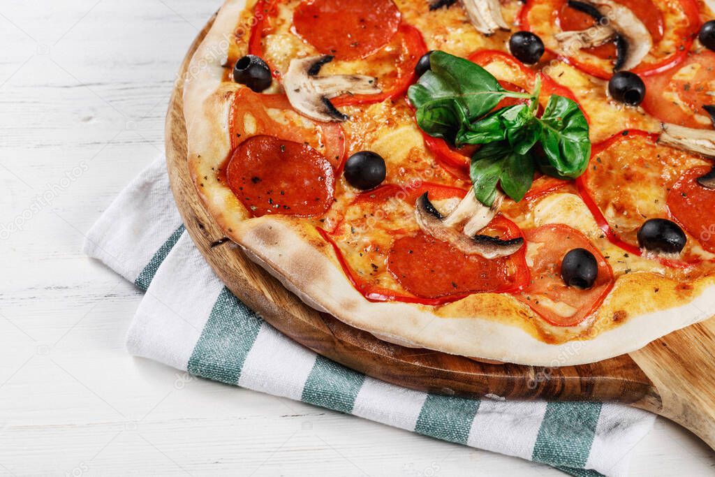 Close-up view of  ITALIAN PIZZA on wooden table. True hot tasty PIZZA with salami, mushrooms, basil, olives, pepper and cheese. Nice for menu Pizzeria. High quality  