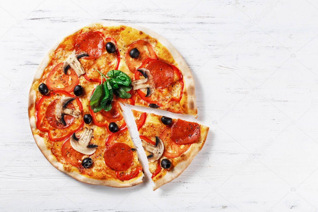 Top view of  ITALIAN PIZZA on wooden table. True hot tasty SLICED  PIZZA with salami, mushrooms, basil, olives, pepper and cheese. Nice for menu Pizzeria. High quality  