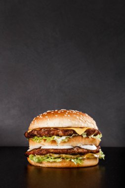 Çifte etli hamburger ve susam tohumlu yumuşak çörek. Instagram tanıtım konsepti için uygun ve ev teslimatı için mükemmel.