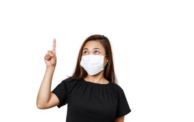 Bir eli yukarıda olan Asyalı kadın beyaz arka plandaki mesaj alanını işaret ediyor. Vücut görünümlü uzun saçlı kadın, Corona virüsünün sağlığını ve güvenliğini korumak için yüz maskesi takıyor..