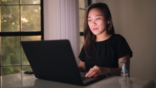 自宅から働くアジアの女性が首をこすり舞い上がる喉を持っています。コロナウイルスを避けるために家と社会的距離を保つ。ノートパソコンで作業する. — ストック動画